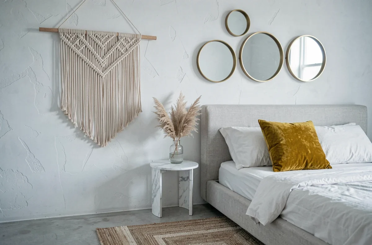 Coin chambre décoré avec des achats en ligne incluant macramé mural, miroirs en laiton et coussin velours moutarde